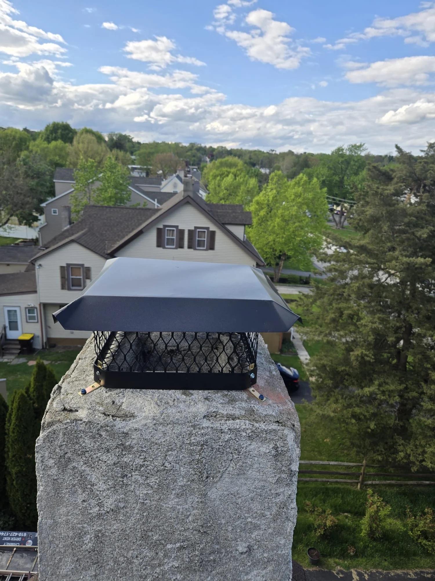 New chimney cap and screen installed on a stone chimney